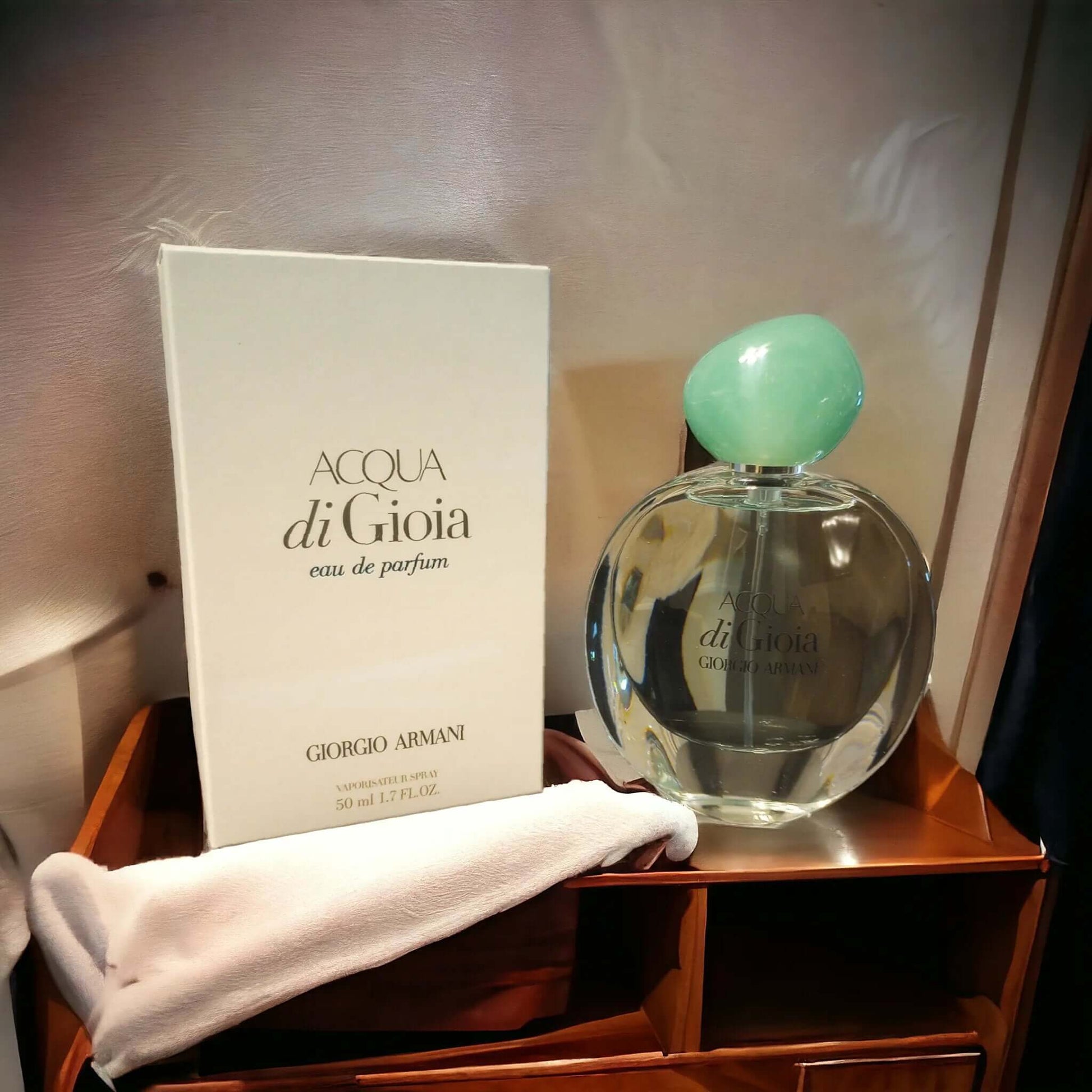 Acqua di Gioia perfume bottle and packaging on a wooden surface