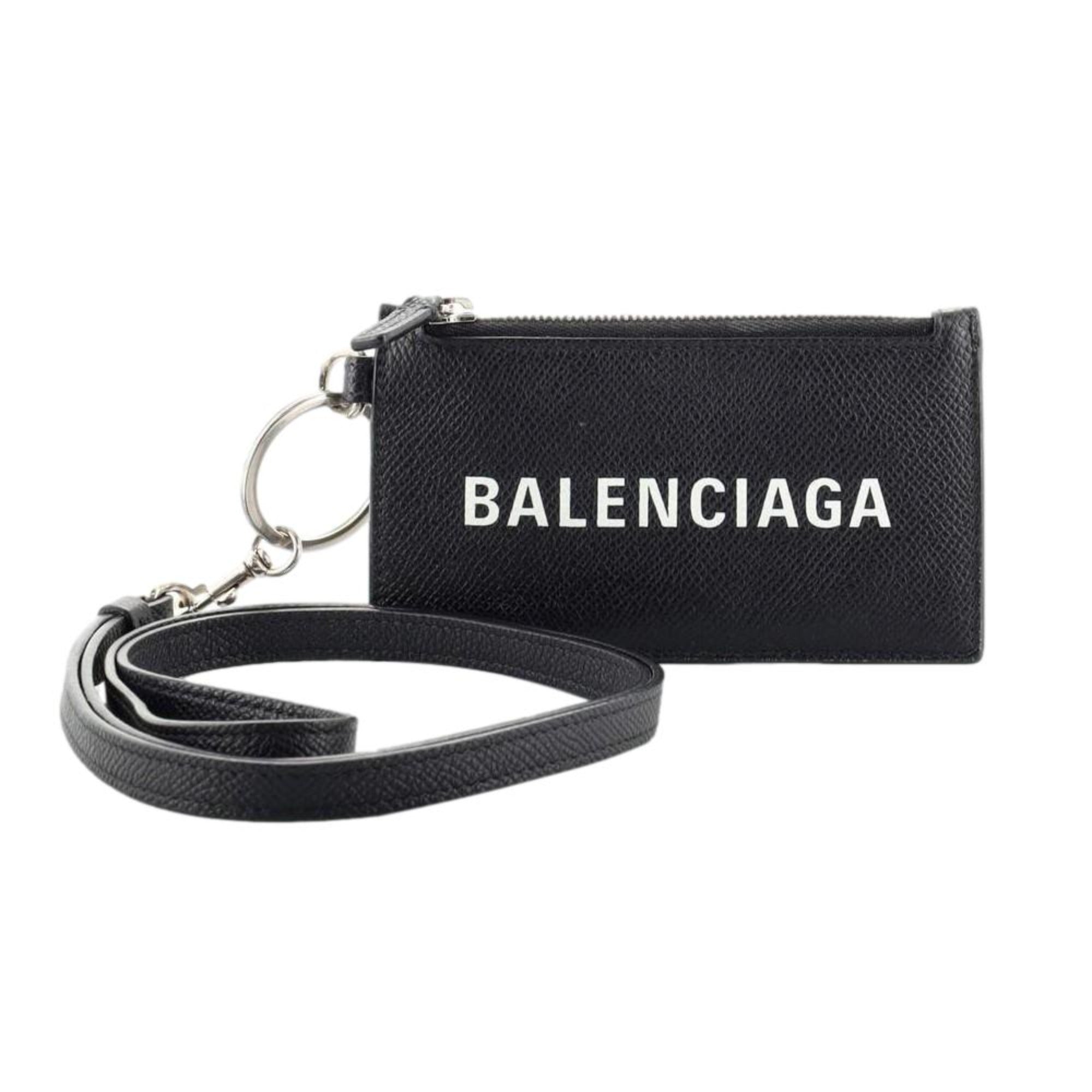 Balenciaga Wallet: Unisex Black Wallet & Card Holder with Lanyard -  Made from black textured leather, this Balenciaga Wallet and card case has a zipped pouch and four card slots, complete with a detachable lanyard for easy portability.Model: 594548Black Calfskin leatherWhite Balenciaga logoBlack leather interior liningFour card slotsTop zipper pocket Detachable leather lanyardStrap drop: 23" Measurements: 5.1 x 0.5 x 3" (LWH)Includes authenticity cardsMade in Italy Shop Bags 