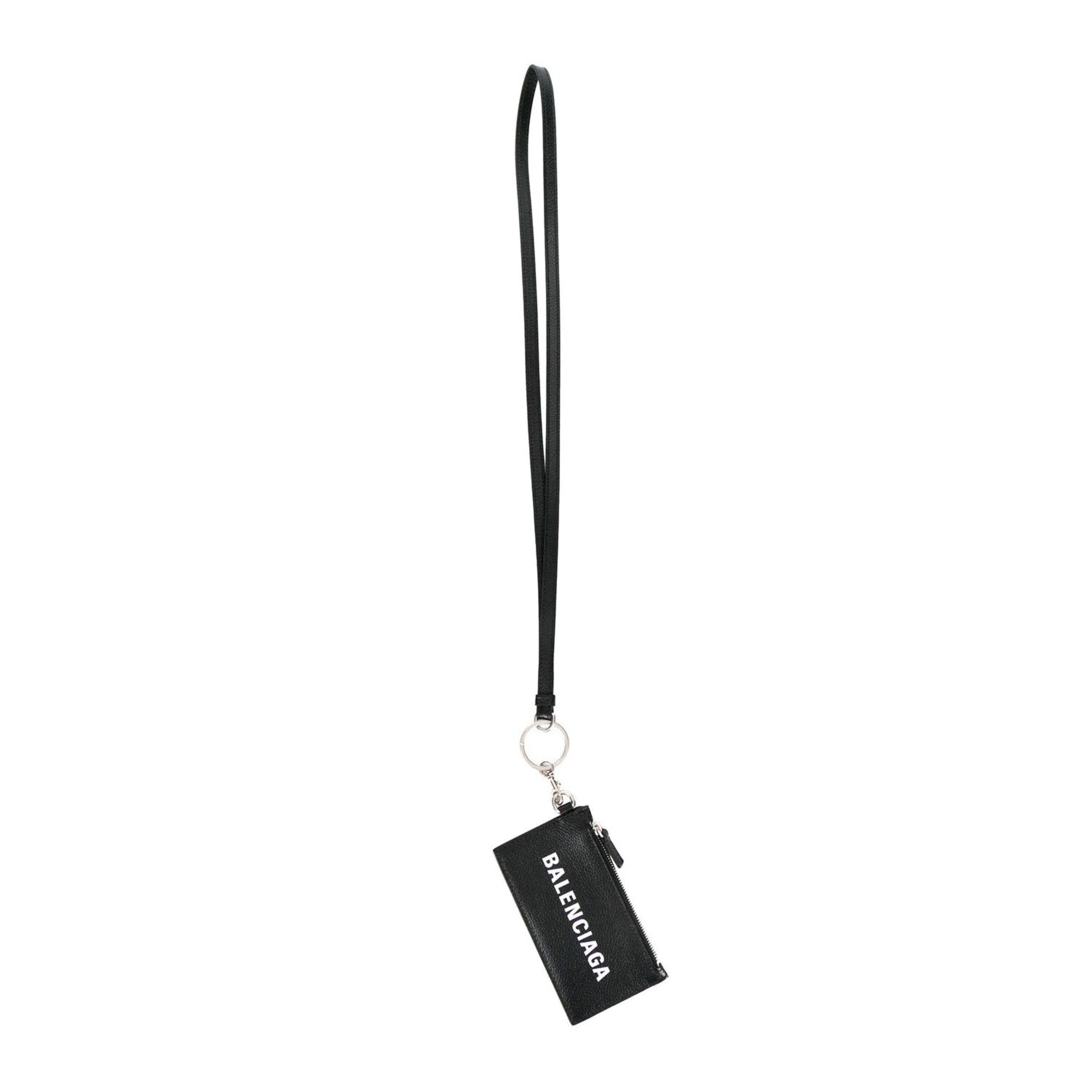 Balenciaga Wallet: Unisex Black Wallet & Card Holder with Lanyard -  Made from black textured leather, this Balenciaga Wallet and card case has a zipped pouch and four card slots, complete with a detachable lanyard for easy portability.Model: 594548Black Calfskin leatherWhite Balenciaga logoBlack leather interior liningFour card slotsTop zipper pocket Detachable leather lanyardStrap drop: 23" Measurements: 5.1 x 0.5 x 3" (LWH)Includes authenticity cardsMade in Italy Shop Bags 