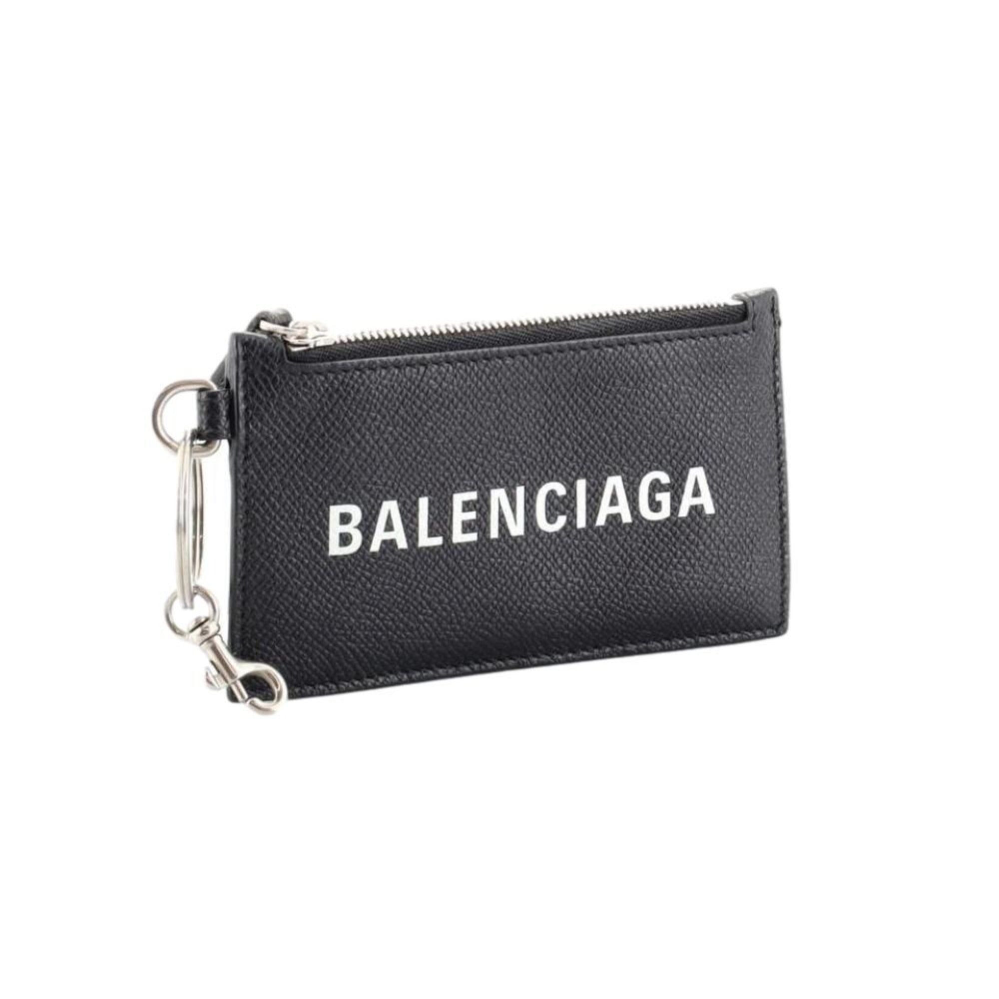 Balenciaga Wallet: Unisex Black Wallet & Card Holder with Lanyard -  Made from black textured leather, this Balenciaga Wallet and card case has a zipped pouch and four card slots, complete with a detachable lanyard for easy portability.Model: 594548Black Calfskin leatherWhite Balenciaga logoBlack leather interior liningFour card slotsTop zipper pocket Detachable leather lanyardStrap drop: 23" Measurements: 5.1 x 0.5 x 3" (LWH)Includes authenticity cardsMade in Italy Shop Bags 