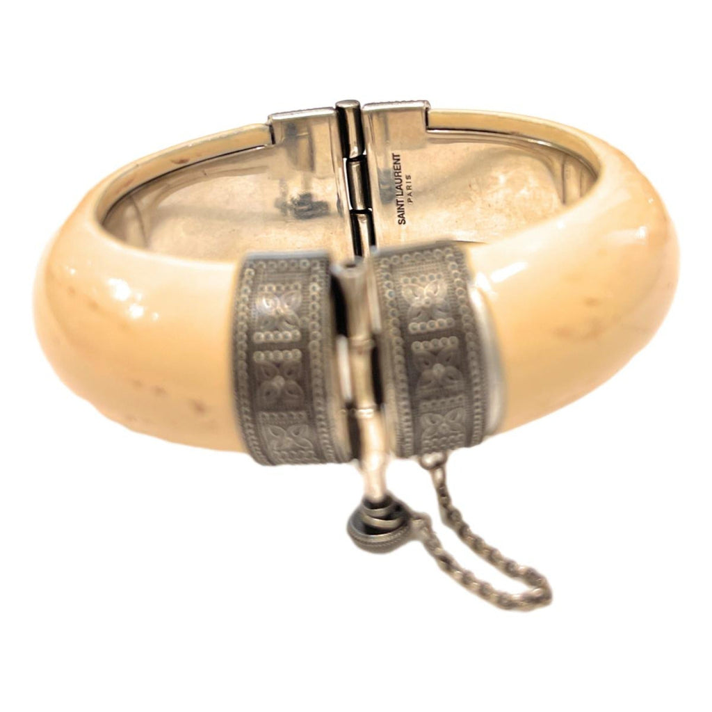 Elegant Saint Laurent Bracelet - Womens Ivory Silver Bangle Bracelet -  This Saint Laurent bangle Bracelet features a blend of oxidized silver brass and ivory-toned resin. Its versatile design complements daily wear and adds a refined touch to your ensemble for special events.Model number: 603598Size: MediumTextured ivory-colored resinSilver oxidized brassScrew-pin closureDimensions: 6.25" inner circumference, 3" outer length, 1" height, 0.5" widthIncludes authenticity cardsMade in Italy Shop Bags 
