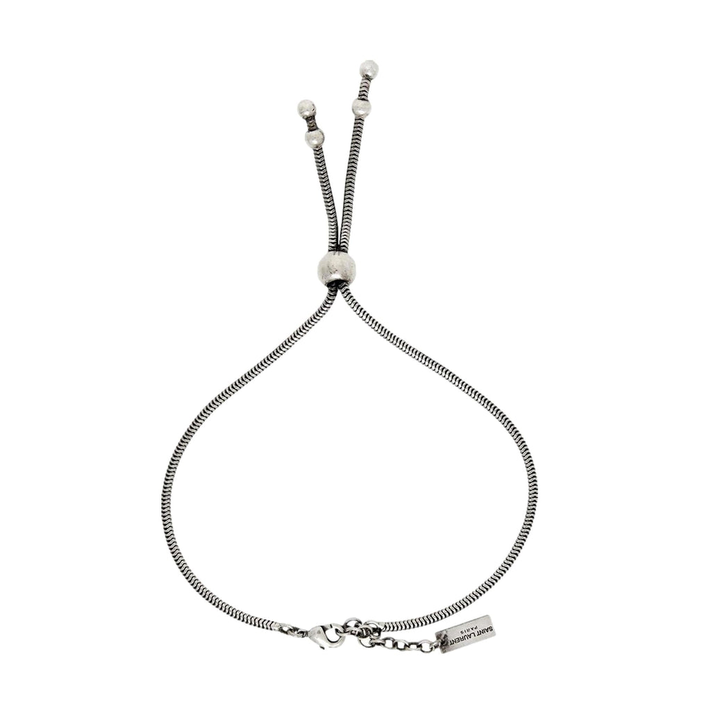 Elegant Tie Bracelet, Shop Bags - Saint Laurent Silver Bolo Style -  The Saint Laurent Silver bolo Tie Bracelet offers a sophisticated twist to elevate your look. Featuring a sleek silver-tone design combined with the iconic bolo tie style, it strikes a refined balance between casual wear and elegant appeal.Model Number: 667365Silver-tone chainLobster claw closureMetal tag with logo embossedAuthenticity cards and box includedMade in Italy Shop Bags 