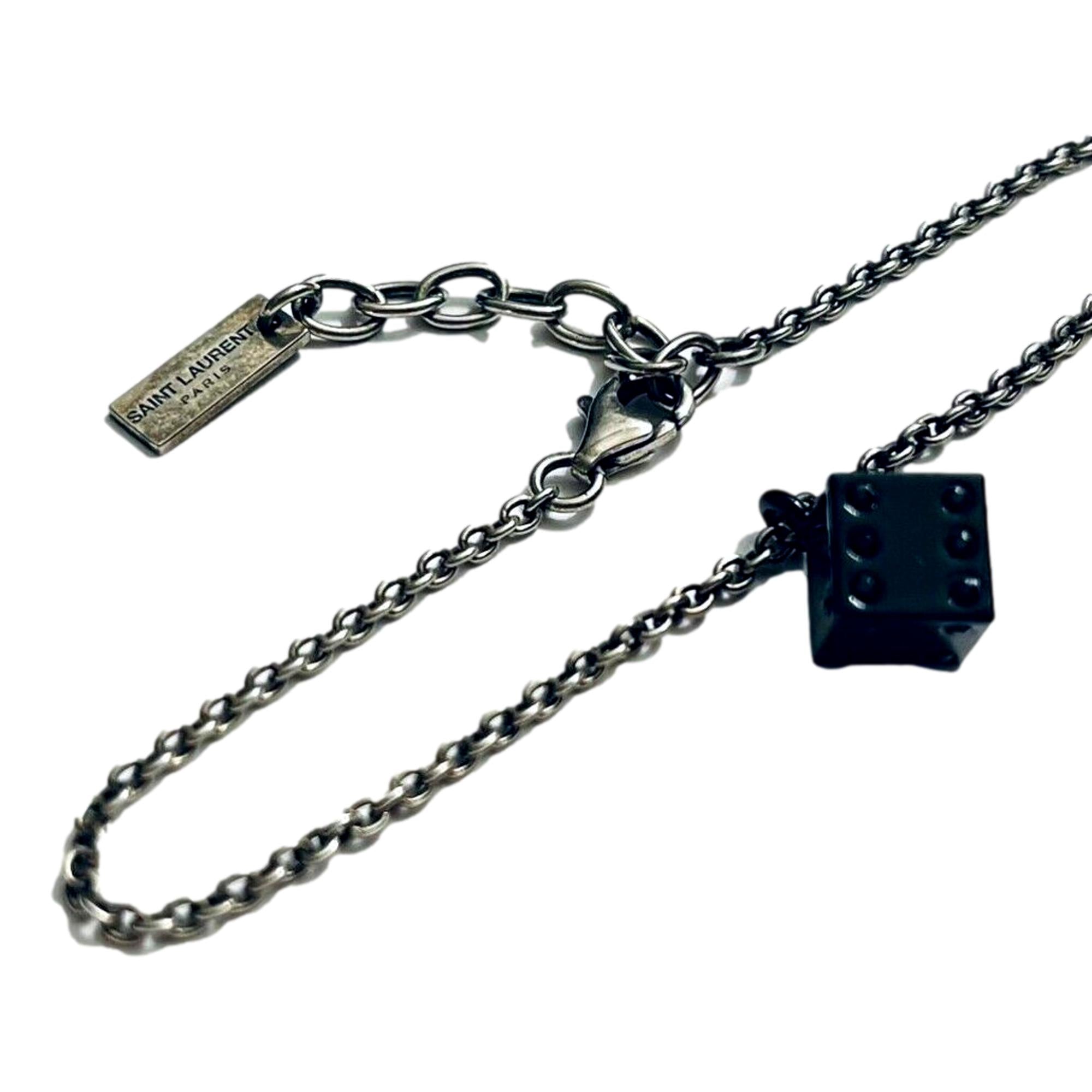 Sleek Saint Laurent Bracelet: Viscose Radio Black & Silver Charm -  The Saint Laurent Des Toile Viscose Radio Chain Bracelet offers a sleek, sophisticated touch to your look. Featuring a silver-tone design complemented by a black dice charm, this bracelet adds subtle boldness and a hint of fortune to your style. Model: 571859Silver-tone chainBlack dice charmLobster claw closureMetal tag with logo embossedIncludes authenticity cards and boxMade in Italy Shop Bags 