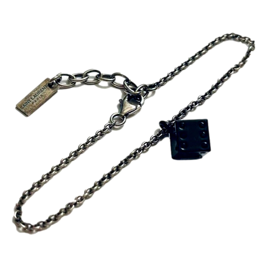 Sleek Saint Laurent Bracelet: Viscose Radio Black & Silver Charm -  The Saint Laurent Des Toile Viscose Radio Chain Bracelet offers a sleek, sophisticated touch to your look. Featuring a silver-tone design complemented by a black dice charm, this bracelet adds subtle boldness and a hint of fortune to your style. Model: 571859Silver-tone chainBlack dice charmLobster claw closureMetal tag with logo embossedIncludes authenticity cards and boxMade in Italy Shop Bags 
