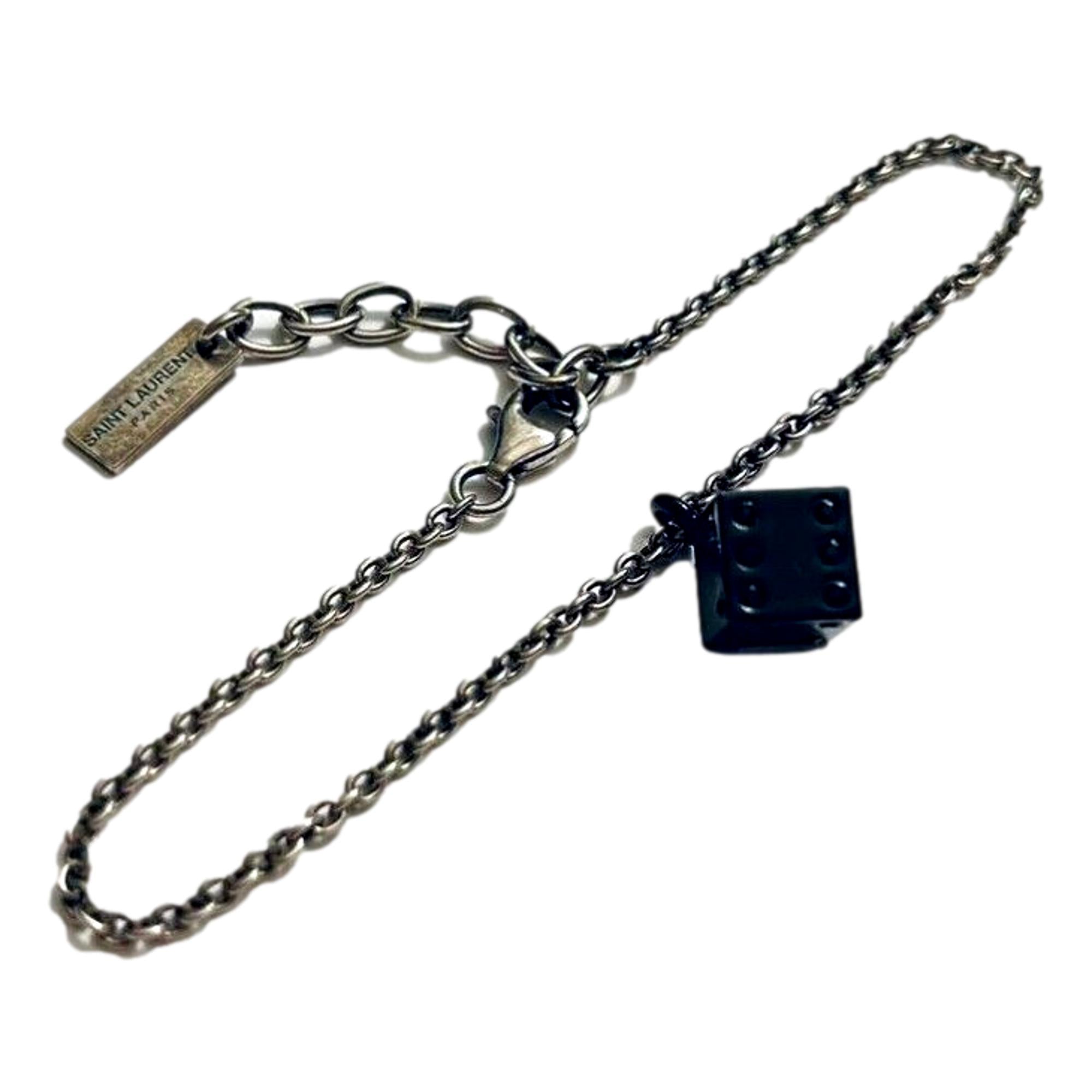 Sleek Saint Laurent Bracelet: Viscose Radio Black & Silver Charm -  The Saint Laurent Des Toile Viscose Radio Chain Bracelet offers a sleek, sophisticated touch to your look. Featuring a silver-tone design complemented by a black dice charm, this bracelet adds subtle boldness and a hint of fortune to your style. Model: 571859Silver-tone chainBlack dice charmLobster claw closureMetal tag with logo embossedIncludes authenticity cards and boxMade in Italy Shop Bags 