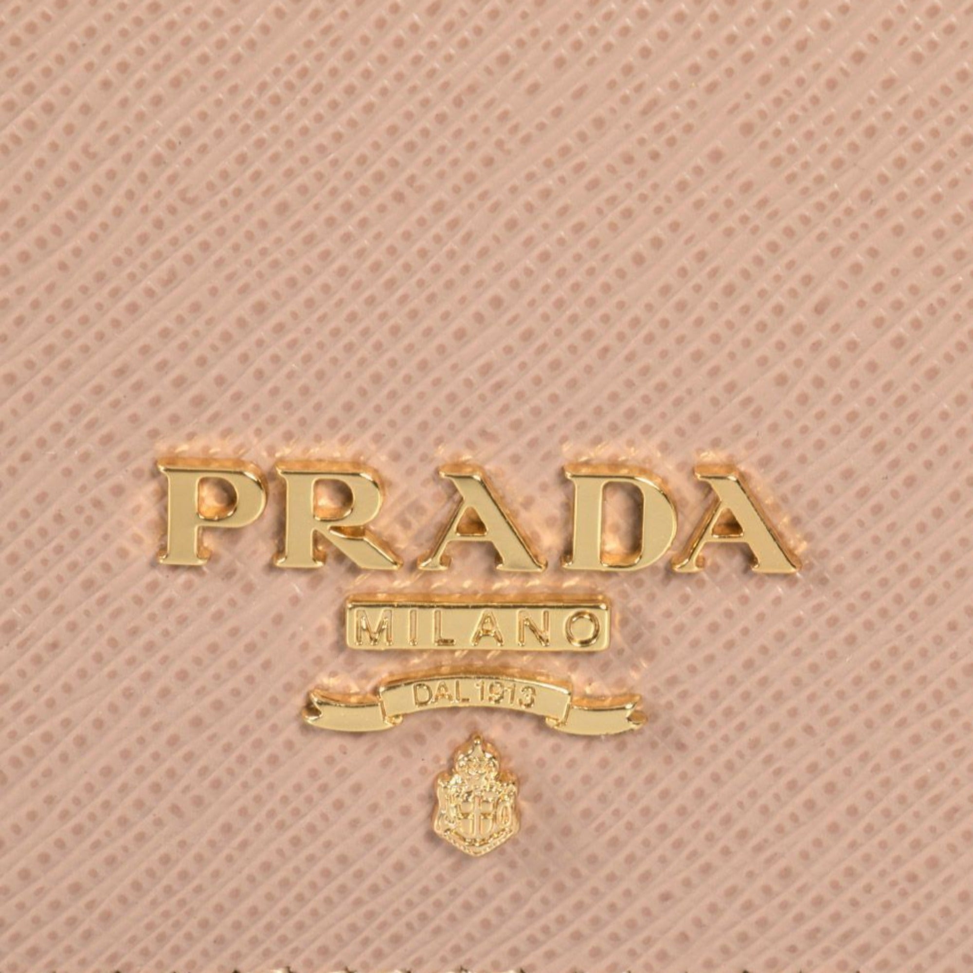 Prada Saffiano Leather Card Holder – Elegant Beige with Gold Logo -  This Prada saffiano beige Card Holder wallet is the perfect size for your personal necessities. The gold Prada Milano logo looks amazing with the beige saffiano leather. Includes authenticity cards and Prada box. Model: 1MC122Cammeo beige saffiano leather Gold-tone hardwareGold Prada Milano logo Snap closureThree card slotsMeasurements: 4.5" x 1" x 2.5" (LWH)Includes authenticity cards and Prada box Made in Italy Shop Bags 