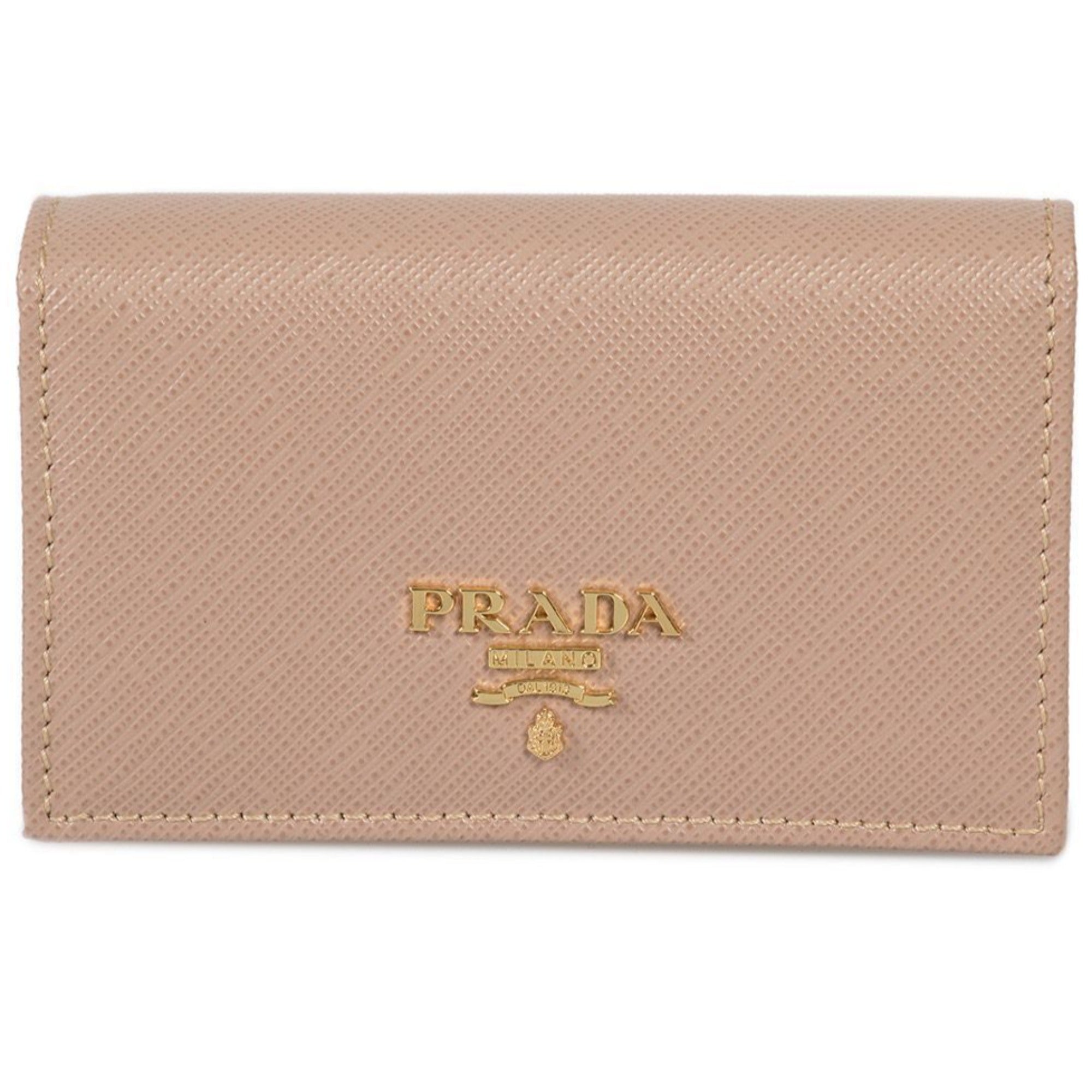 Prada Saffiano Leather Card Holder – Elegant Beige with Gold Logo -  This Prada saffiano beige Card Holder wallet is the perfect size for your personal necessities. The gold Prada Milano logo looks amazing with the beige saffiano leather. Includes authenticity cards and Prada box. Model: 1MC122Cammeo beige saffiano leather Gold-tone hardwareGold Prada Milano logo Snap closureThree card slotsMeasurements: 4.5" x 1" x 2.5" (LWH)Includes authenticity cards and Prada box Made in Italy Shop Bags 