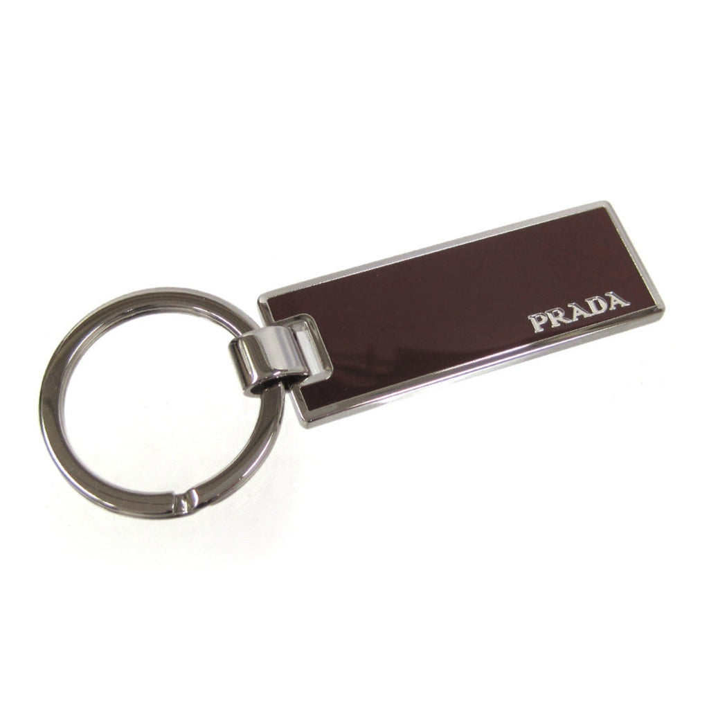 Prada Rubino Red Enamel Keychain - Luxury Silver Metal Keyring -  This Prada Keychain features a sleek rectangular silver-tone base topped with deep burgundy red enamel. Designed for both men and women, it offers a sophisticated way to secure keys or accessorize a bag with a touch of luxury.Model number: 2PS021Rubino red enamelSilver-tone metal and key ring, 1.1" diameterMeasurements: 0.6 x 0.1 x 2" (LWH)Includes authenticity cards and Prada boxMade in Italy Shop Bags 